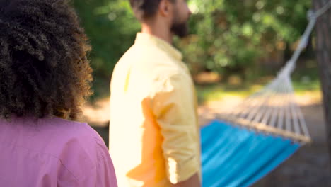 Young-black-woman-covers-man-eyes-to-surprise-him-in-the-woods.-Pretty-female-with-afro-hair-outdoors.