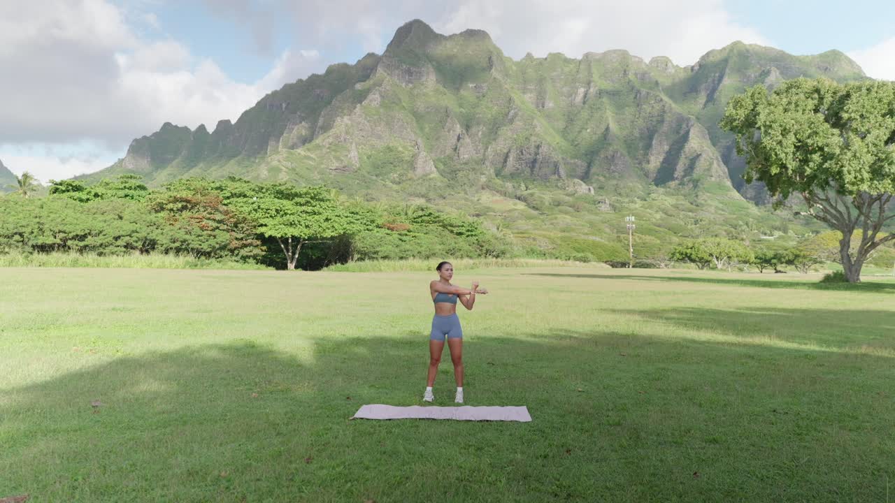Fitness model stretching arms in front of mountain