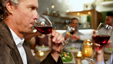 Happy-couple-toasting-wine-glasses-while-friends-interacting-in-background-4K-4k