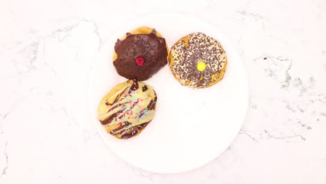 las deliciosas rosquillas decoradas con chocolate aparecen y desaparecen del plato blanco.