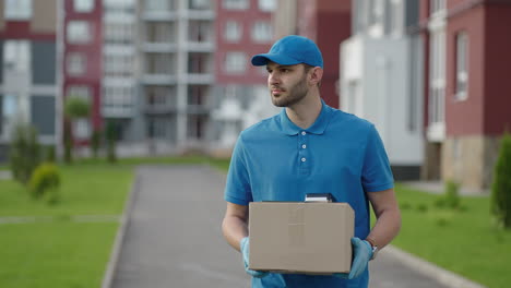 A-delivery-man-carries-a-package-to-customers-in-a-residential-area.-Grocery-delivery-and-online-shopping