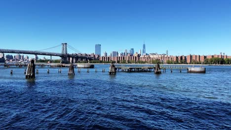 Muelle-Norte-De-Williamsburg-De-La-Ciudad-De-Nueva-York-Con-Vistas-Al-Río-Este,-Al-Puente-Williamsburg-Y-Al-Horizonte-De-Manhattan-Con-Un-Centro-De-Comercio-Mundial-En-Un-Día-De-Verano-Claro-Y-Soleado