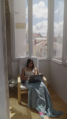 mujer trabajando en una computadora portátil en un balcón