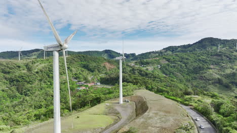 aerial footage of elongated white wind turbines atop rolling hills, capturing the beauty of green energy in motion