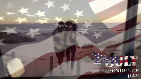 Mixed-race-couple-smiling-at-beach-with-US-flag-waving-and-independence-date-foreground