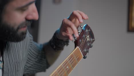 man tuning an acoustic guitar