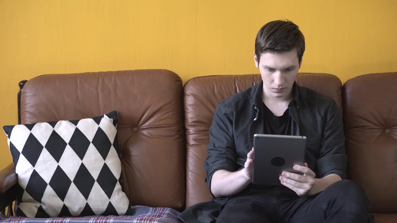 소파 에 태블릿 을 사용 하는 젊은 남자