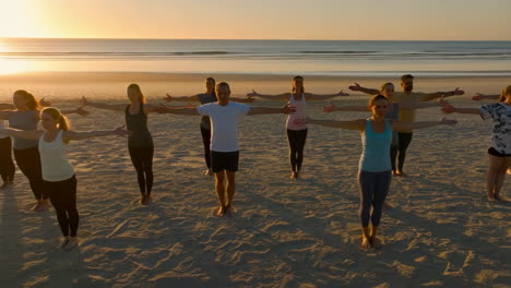 group yoga and wellness session on a beach at sunrise
