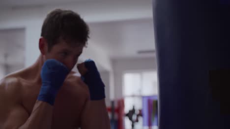 caucasian man using punchbag in boxing gym