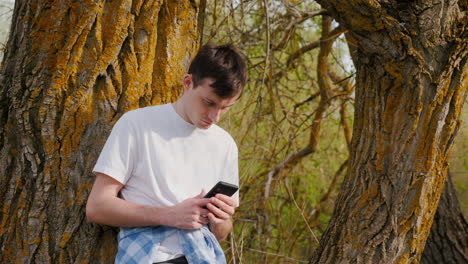 man using phone near trees in a forest