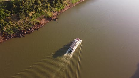 ferry tourist boat crossing iguazu river at sunset, argentina and brazil border