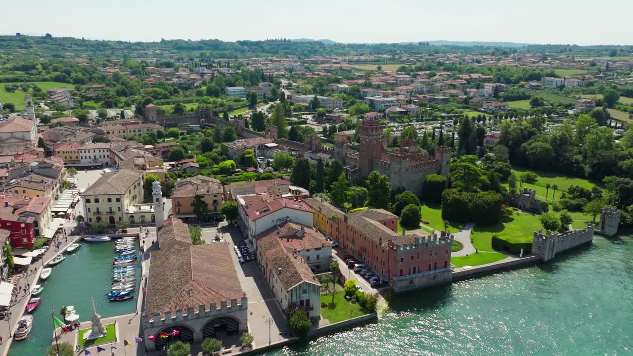 A breathtaking aerial shot of Lazise’s vibrant harbor and the imposing medieval castle on the eastern shore of Lake Garda, Italy