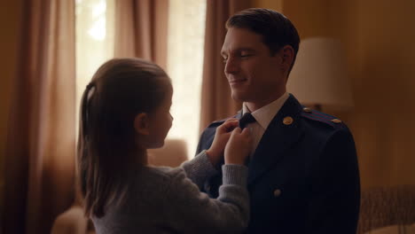 a daughter helps her father with his uniform