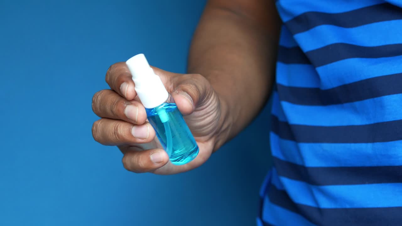 persona que sostiene una botella de spray de desinfectante para manos