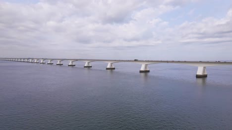 beautiful drone flight over the water from the eastern schelde to the zeeland bridge under a cloudy sky