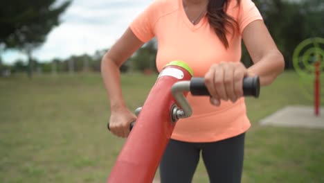 the woman is employing a pedal exercise apparatus while at the park - slow motion