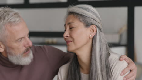 suffering middle aged woman leaning her head on man's shoulder