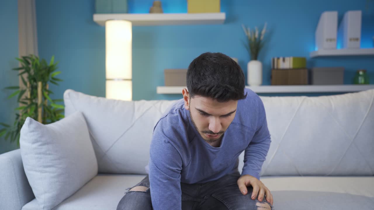 Young man watching horror movie on smartphone alone at home.