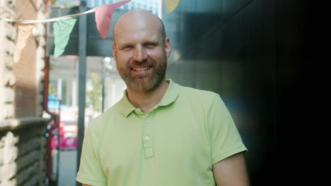 smiling bald man in a green polo shirt