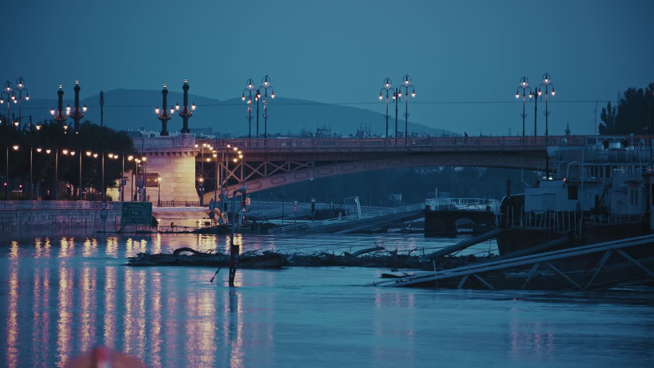 다리 불빛은 침몰 된 구조물이 보이는 아침 파란 하늘 아래 평온한 홍수 물에 반사됩니다.