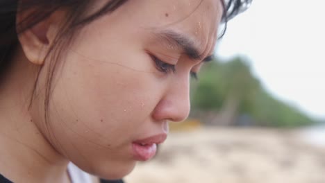 close-up of young woman's face as she experiences anxiety attack while crying at windy, outdoor setting. -static shot