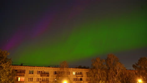 Vibrant-Northern-lights-above-city-suburbs-buildings,-time-lapse