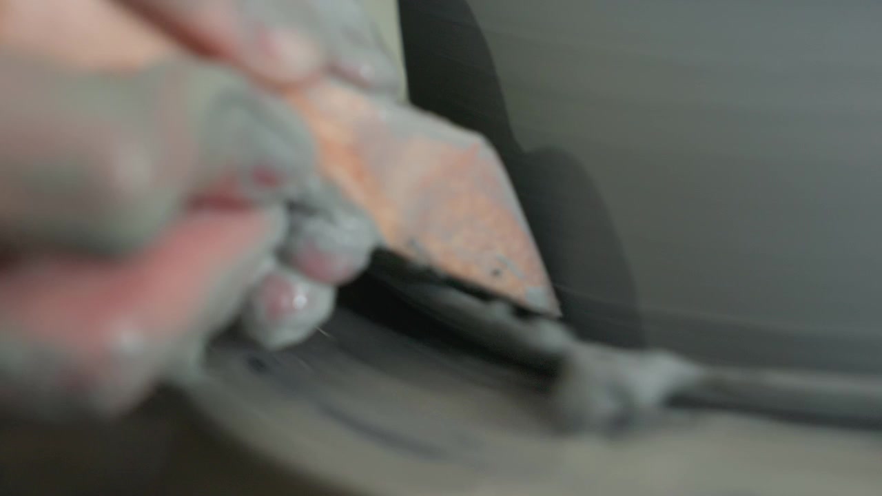 Pottery scraping and smoothing rim closeup, caucasian fingers guiding scraper to remove slip and shavings, damp clay buildup, soft light, meditative finishing process, focused studio environment