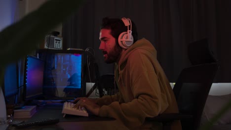 Male-using-PC-and-gaming-using-keyboard-and-mouse-leaning-in-and-concentrating