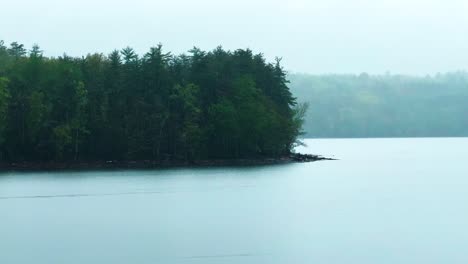 heavy-rain-during-spring-time,-on-a-pristine-mountain-lake-with-a-stunning-pine-forest,-on-an-atmospheric-magical-day