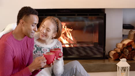 diverse couple enjoying hot cocoa by cozy fireplace during christmas celebration