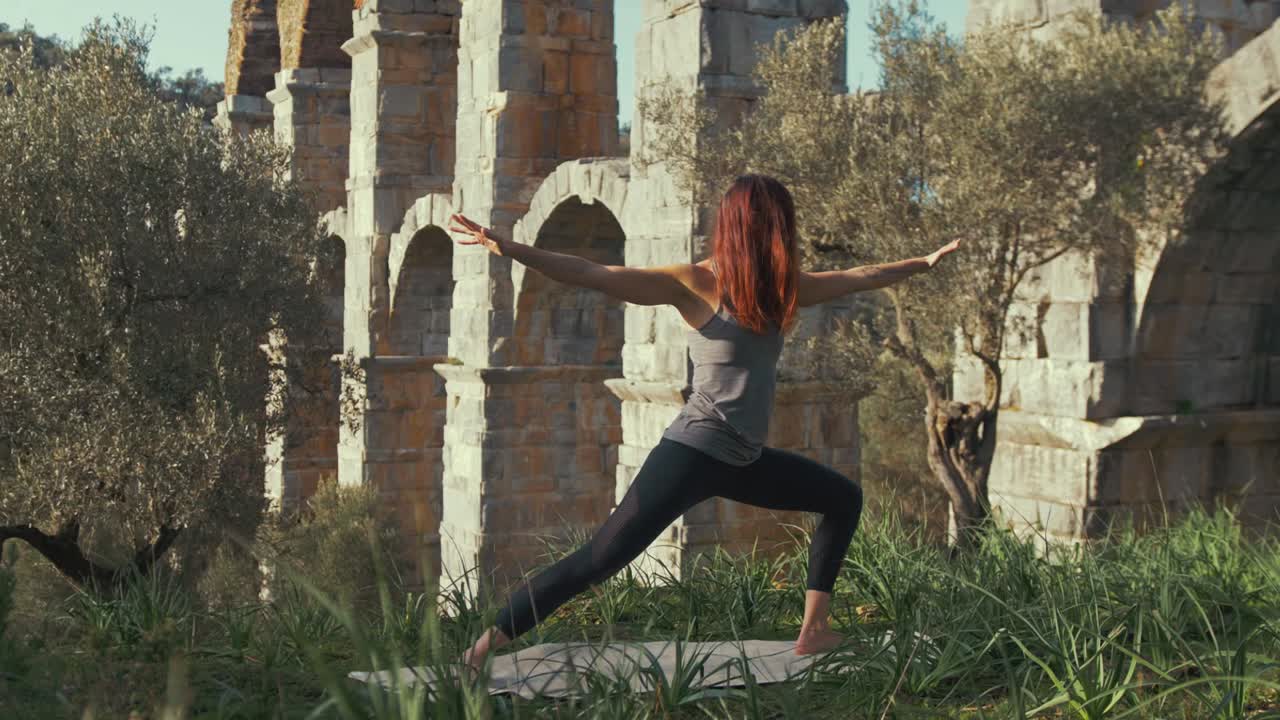 l'atleta femminile esegue esercizi di routine di yoga presso l'antico acquedotto