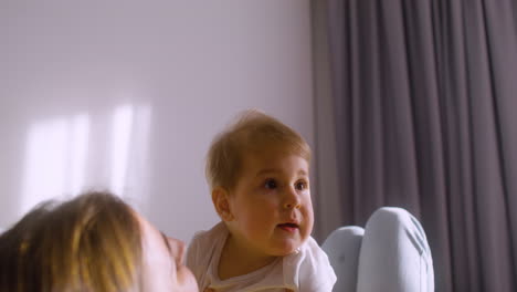 Rear-View-Of-Woman-Lying-On-The-Sofa-At-Home-While-Playing-With-Her-Baby