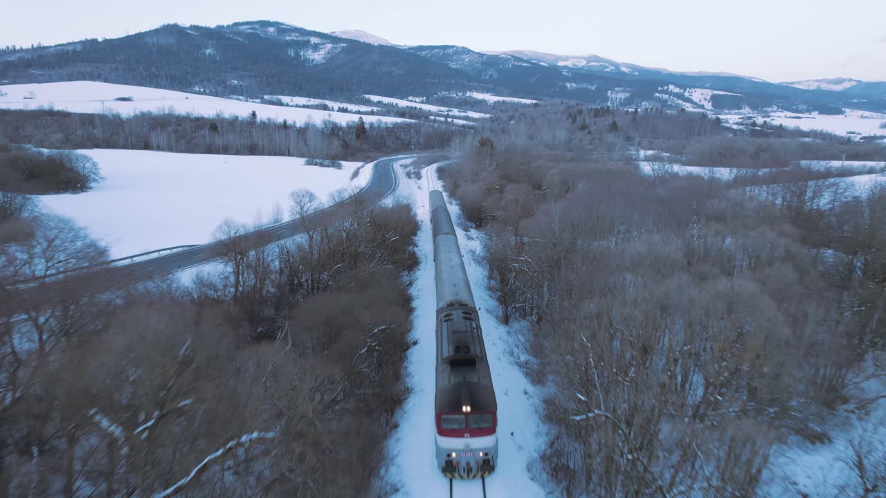 Dronekuva nopeasti liikkuvasta junasta valtavassa lumivalkoisessa maisemassa.