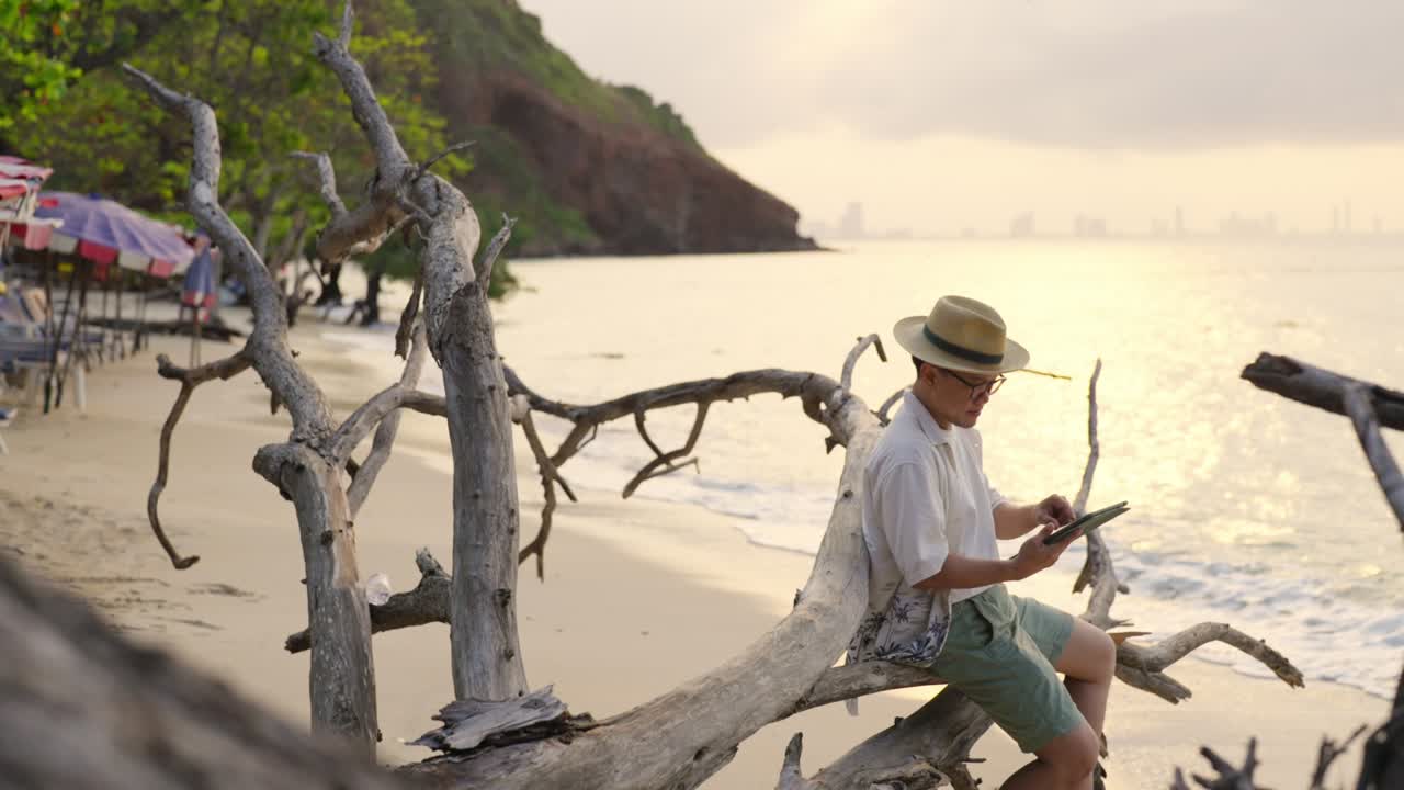 4K Happy Asian businessman working on digital tablet while travel at tropical beach.