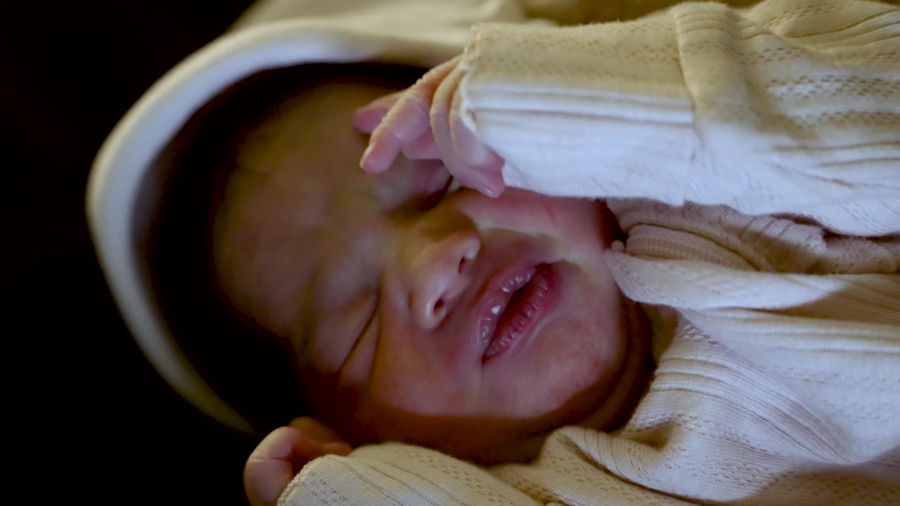 Close up of a newborn baby girl sleeping peacefully with her hand gently resting on her face