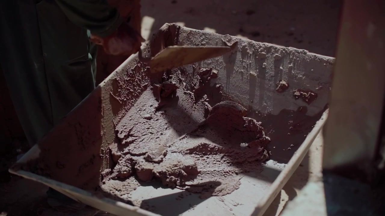Cement and sand plaster is mixed in a metal tray at a rustic construction site in Brasilia, Federal District, Central West Region, Brazil, South America, static shot.