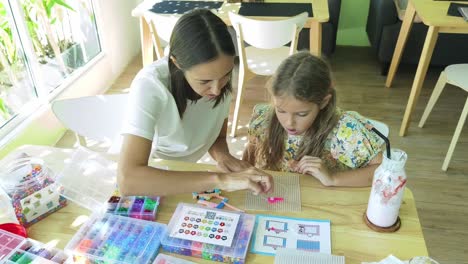 mother and daughter beading activity in a cafe