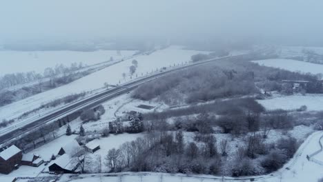 Vista-Aérea-De-La-Campiña-Alemana-Cubierta-De-Nieve-A-Lo-Largo-De-La-Carretera---Camiones