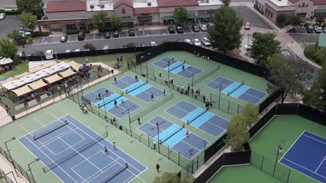 national pickleball tournament in santa clarita with multiple courts of players playing the popular sport, aerial pullback