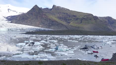 國際氣候研究員在星座船上穿過大冰川湖, 填滿冰山在fjallsárlón 冰島 表明全球暖化和氣候變化