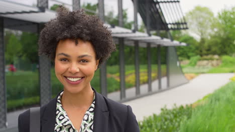 portrait of smiling businesswoman standing outside modern office building