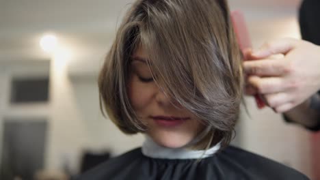 Professioneller-Friseur,-Stylist,-Der-Die-Haare-Einer-Kundin-Kämmt-Und-Eine-Haarspange-Zum-Fixieren-Der-Frisur-Im-Professionellen-Friseursalon-Verwendet.-Schönheits--Und-Haarpflegekonzept