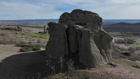 Spinning-aerial-drone-view-of-a-rounded-red-sandstone-rock-with-an-isolated-Zafra-castle-at-the-back