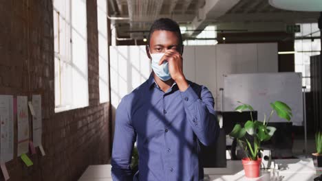 Retrato-De-Un-Hombre-De-Negocios-Afroamericano-Tomando-Una-Mascarilla-Mirando-A-La-Cámara-Y-Sonriendo