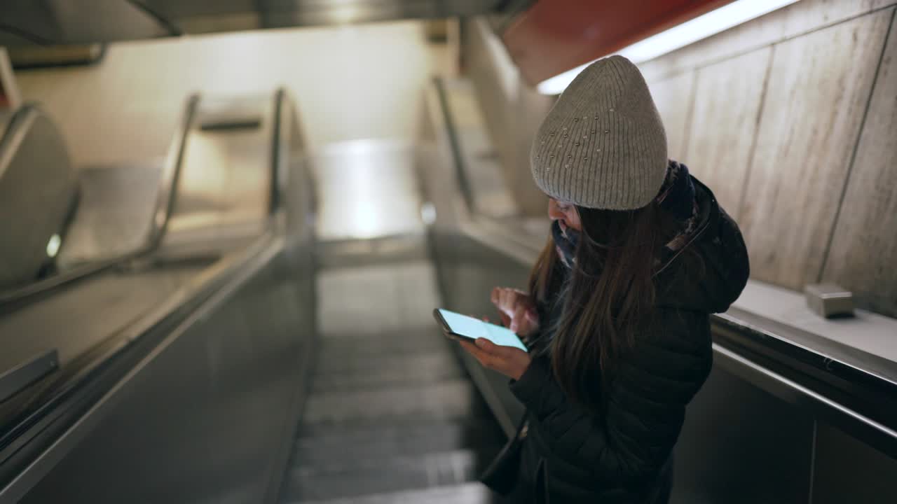 una joven usando un teléfono inteligente durante el descenso en el metro. 4k