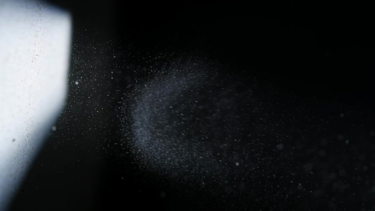 Luce rettangolare brillante a sinistra che emette particelle, nuvola che cresce e si dirada attraverso uno studio buio.