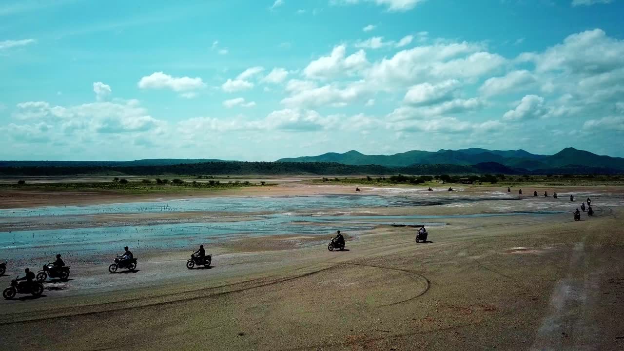 gente alrededor del lago magadi en kenia durante el recorrido en motocicleta - toma aérea de drones