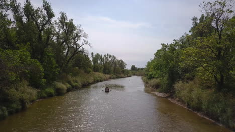 Aerial-shot-of-boat-sailing-in-the-river-in-between-the-jungle