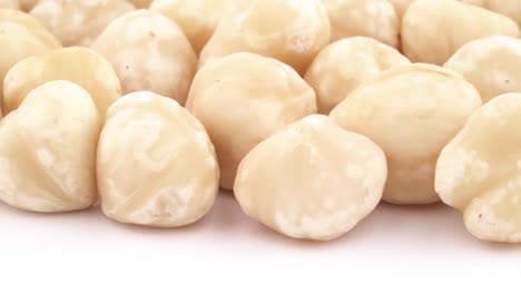horizontal half frame circle shaped pile of blanched hazelnuts. rotating on the turntable, isolated on the white background. close-up. macro.