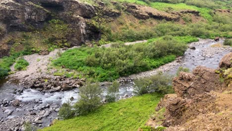 Panorámica-Del-Paisaje-Islandés-Con-El-Río-Que-Fluye-Desde-La-Cascada-De-Glymur.